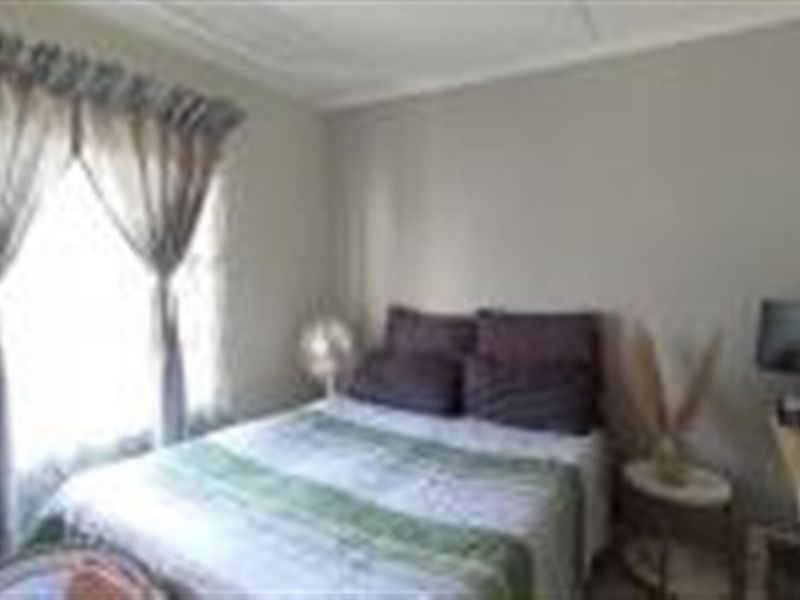 A standard bedroom featuring neutral wall finishes and natural light through a window with installed curtain rails.