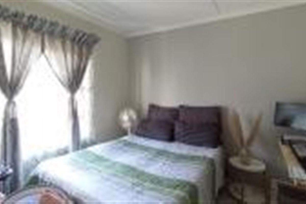 A standard bedroom featuring neutral wall finishes and natural light through a window with installed curtain rails.