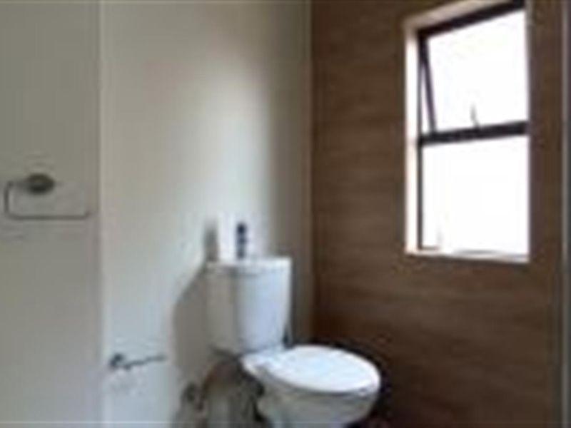 A compact bathroom featuring a modern toilet, towel rail, and wood-look wall cladding, providing a clean and functional space.