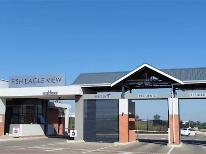 The secure entrance gatehouse of Fish Eagle View complex, featuring controlled access boom gates and a modern brick and metal architectural design.