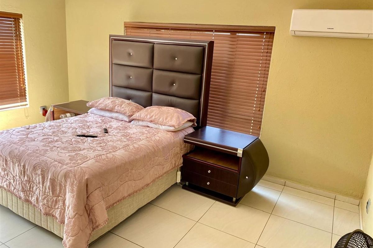 A bedroom featuring tiled flooring, wooden venetian blinds, and a wall-mounted air conditioning unit.