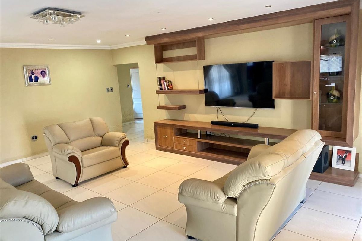 Spacious living room featuring built-in wooden cabinetry, tiled flooring, and recessed ceiling lighting.