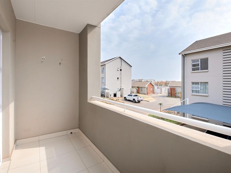 A clean, tiled balcony featuring a metal balustrade and views over the residential complex.