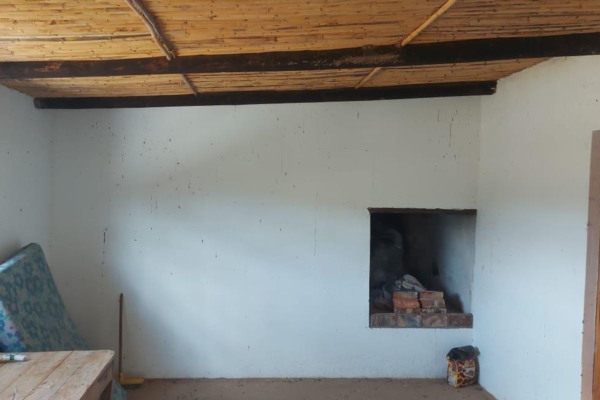 A rustic interior space featuring a traditional reed ceiling with exposed timber beams and a built-in masonry fireplace.