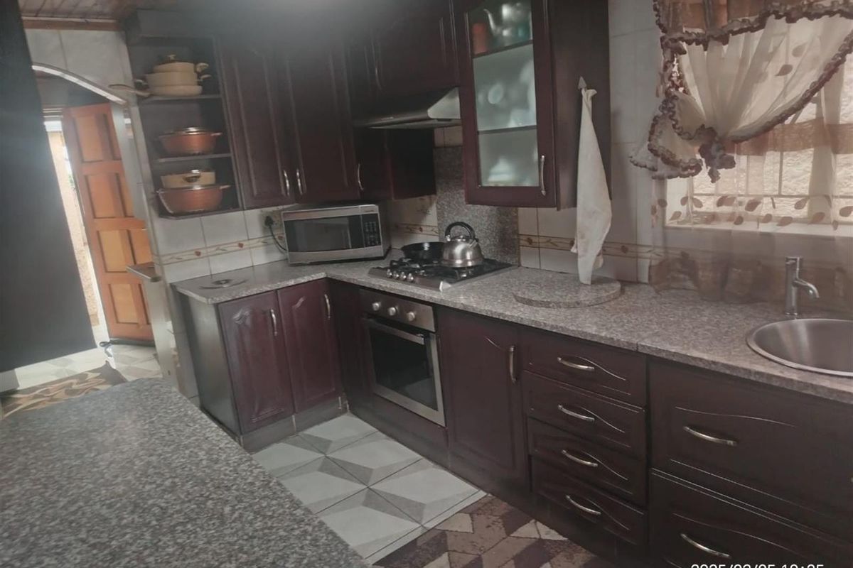 A functional kitchen featuring dark wood cabinetry, granite countertops, a built-in oven with gas hob, and tiled flooring.