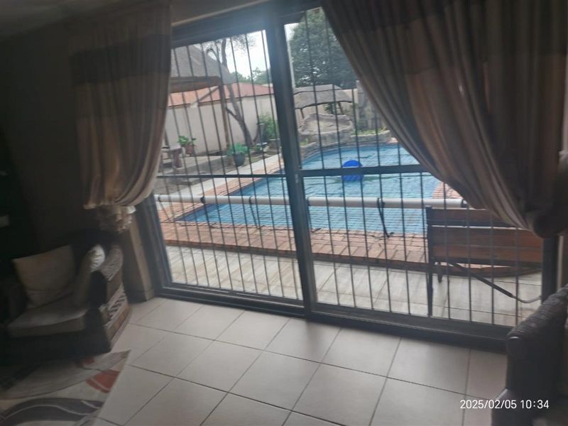 Living area featuring tiled flooring and large sliding glass doors with security gates, providing direct access to the outdoor pool area.