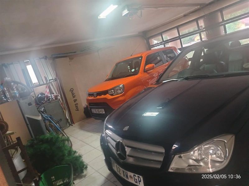 A functional garage space featuring tiled flooring and an automated garage door motor.