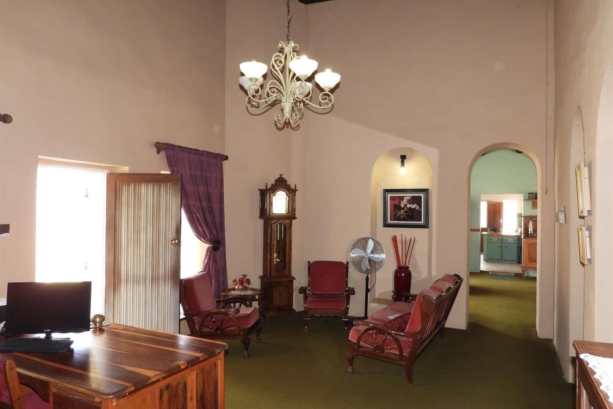 Spacious living area featuring high ceilings, arched doorways, and exposed timber beams, providing a classic and open layout with access to adjacent rooms.
