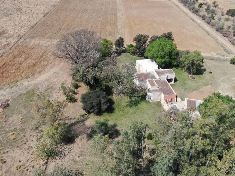 Aerial view of the small holding property, showcasing the main dwelling, surrounding garden, mature trees, and adjacent agricultural land.