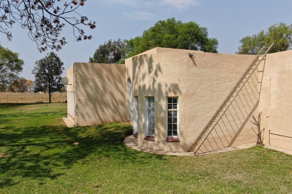 A view of the rear exterior elevation of the small holding, featuring a curved wall design and surrounding lawn area.