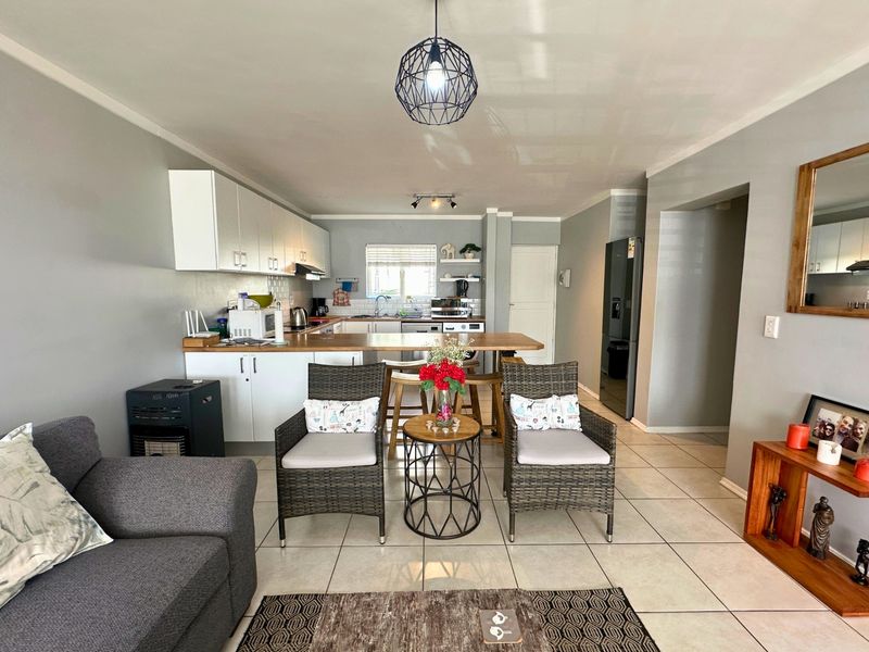 Open-plan living and kitchen area featuring tiled flooring, modern cabinetry, and a functional breakfast bar, creating a cohesive and practical living space.