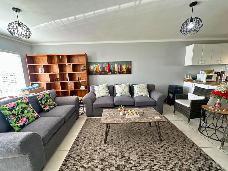 Open-plan living area featuring tiled flooring, modern pendant lighting, and an integrated kitchen space with built-in cabinetry.