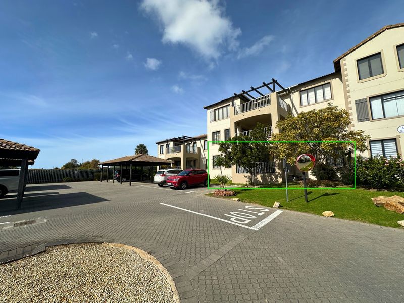 Exterior view of an apartment complex featuring paved parking areas, covered carports, and multi-story residential units with balconies.