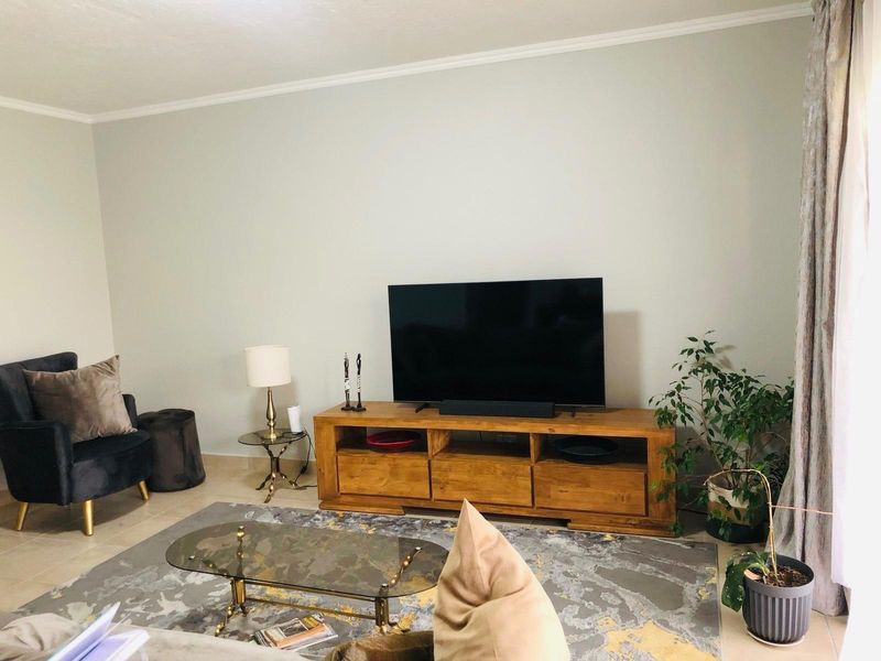A comfortable living room featuring neutral wall tones and tiled flooring, providing a versatile space for relaxation and entertainment.