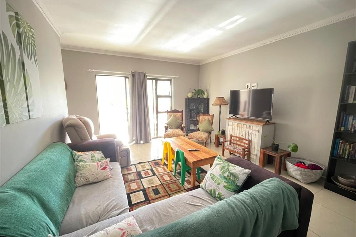 A comfortable living room featuring tiled flooring, crown molding, and sliding glass doors that provide access to the outdoor area.