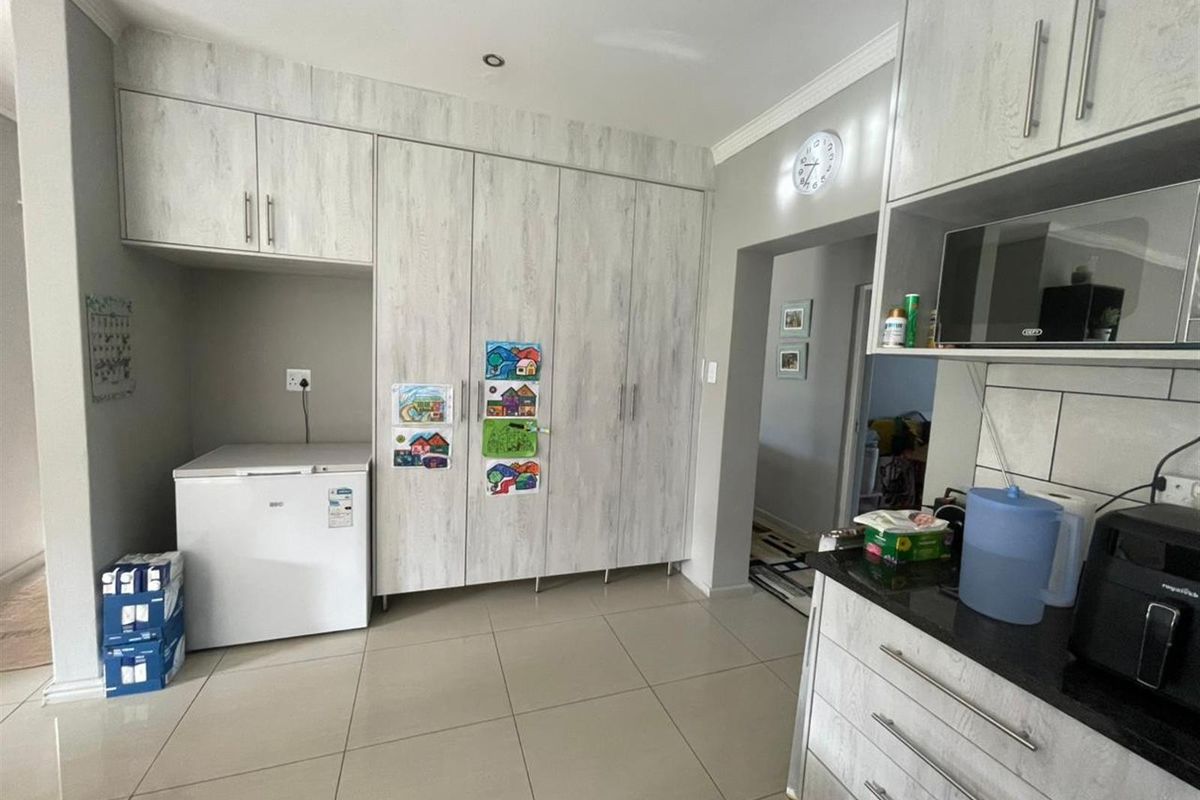 A functional kitchen featuring light wood-grain cabinetry, dark countertops, tiled flooring, and a dedicated space for a chest freezer.