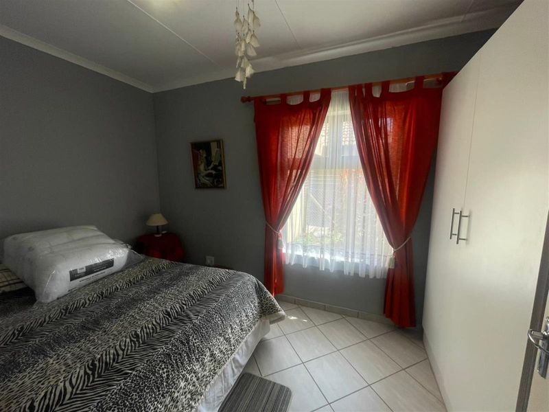 A functional bedroom featuring tiled flooring and a built-in wardrobe, providing essential storage space and a neutral foundation for personal styling.