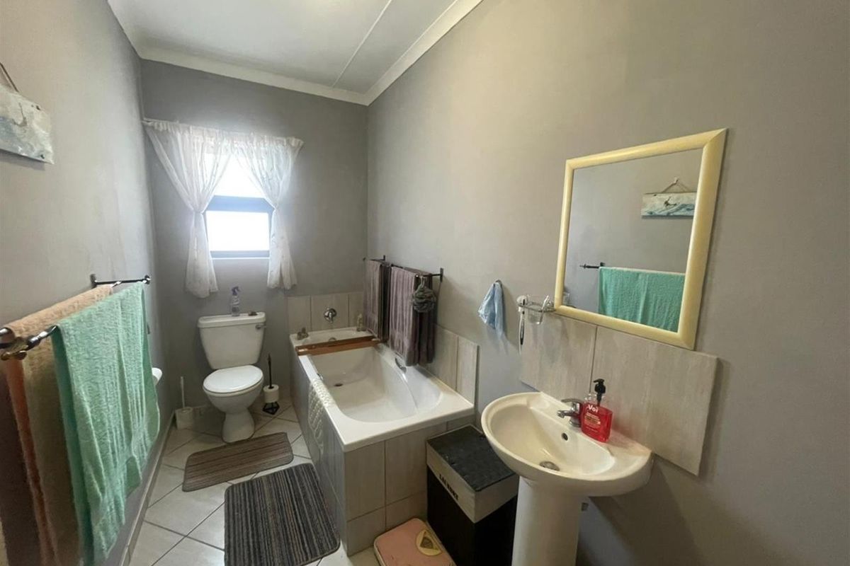 A functional bathroom featuring a pedestal basin, built-in bathtub, and toilet with neutral wall finishes and tiled flooring.