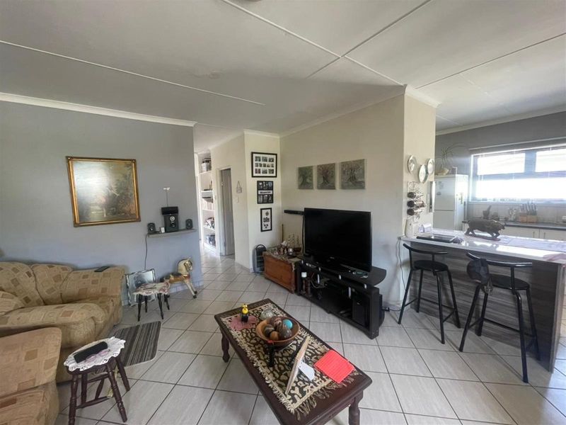 Open plan living area featuring tiled flooring and a breakfast bar connecting to the kitchen, with visible ceiling water staining.