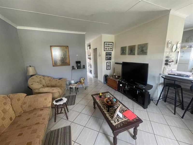 Open plan living area featuring tiled flooring and a breakfast bar, with a visible water stain on the ceiling.