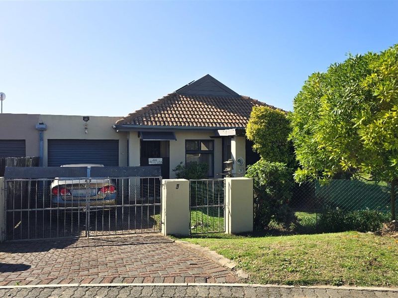 Front elevation of a townhouse featuring a tiled roof, paved driveway, and secure gated entrance with a single garage.