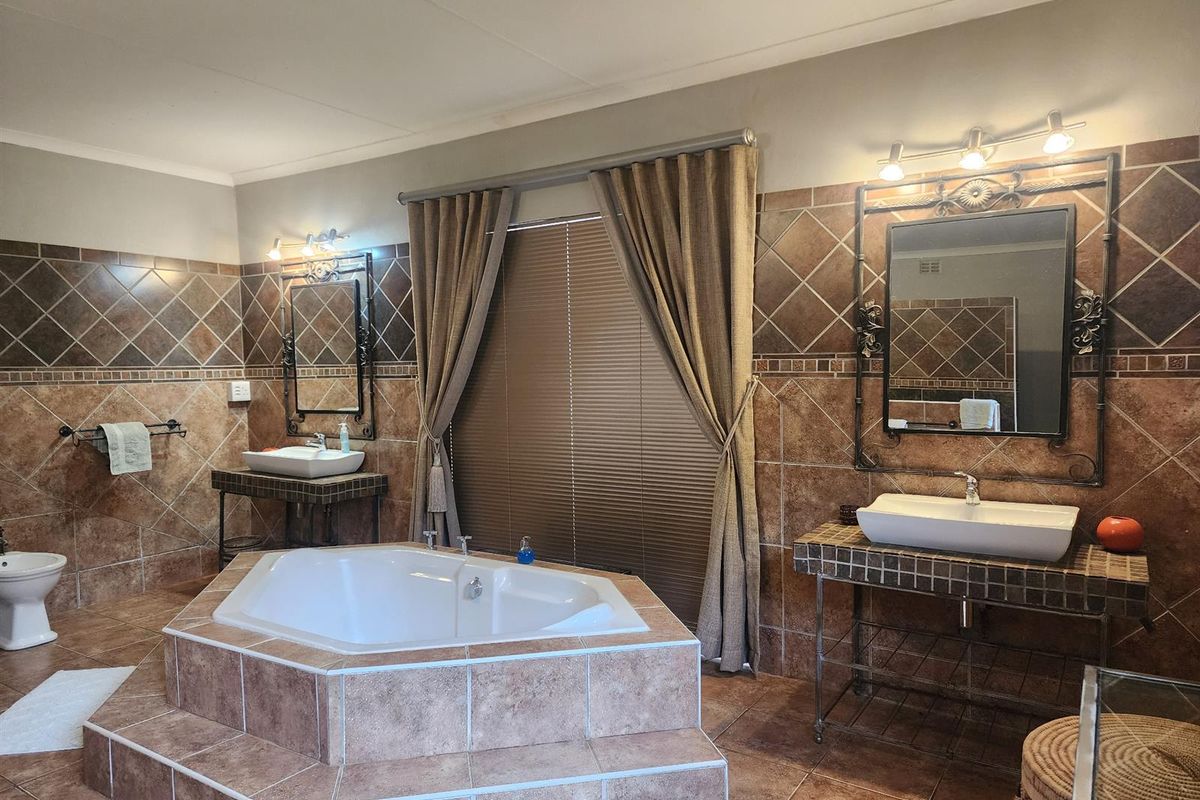 Spacious bathroom featuring a built-in corner bathtub, dual vessel sinks with tiled vanities, and decorative wall tiling throughout.