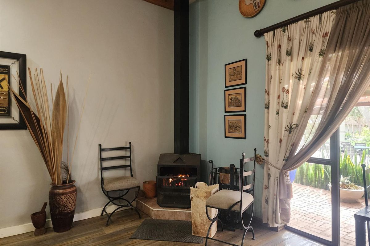 Cozy living area featuring a black freestanding fireplace on a tiled hearth, laminate flooring, and a sliding glass door leading to an outdoor patio.