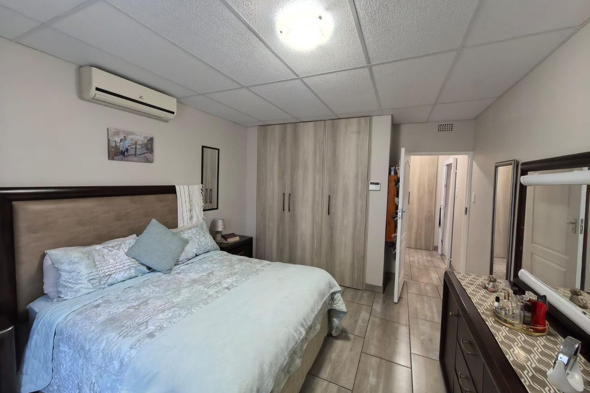 A bedroom featuring built-in wooden cabinetry, tiled flooring, and a wall-mounted air conditioning unit.