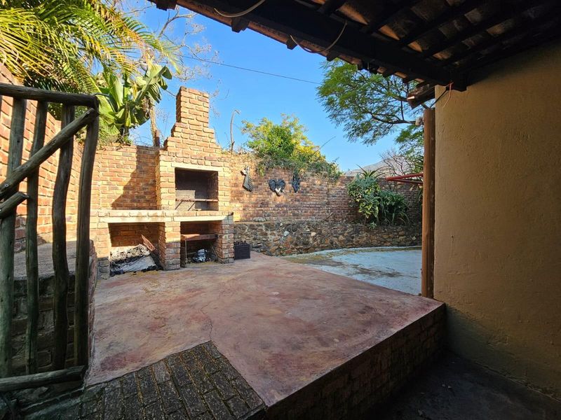 Outdoor patio area featuring a built-in brick braai, concrete flooring, and a rustic brick boundary wall, ideal for outdoor entertaining.