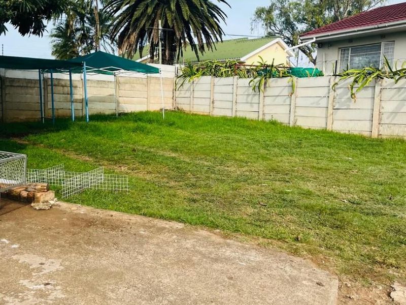 A spacious rear garden featuring a concrete patio area and a precast concrete boundary wall, offering potential for landscaping and outdoor living improvements.