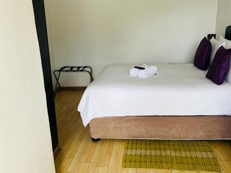 A bedroom featuring light-toned laminate flooring, crown molding, and a wall-mounted air conditioning unit.