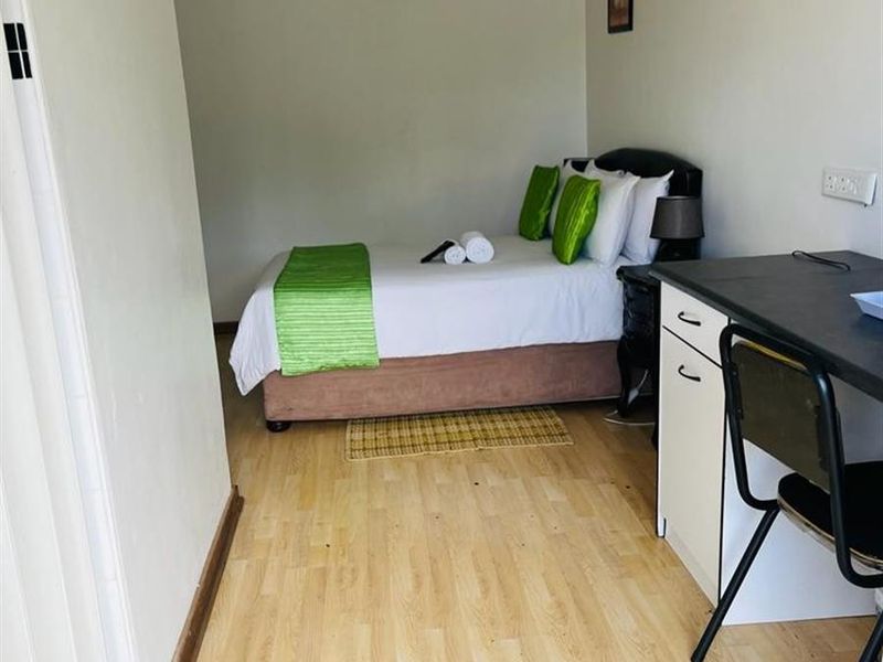 A functional bedroom featuring laminate flooring, an air conditioning unit, and a ceiling light fixture, providing a comfortable and practical living space.