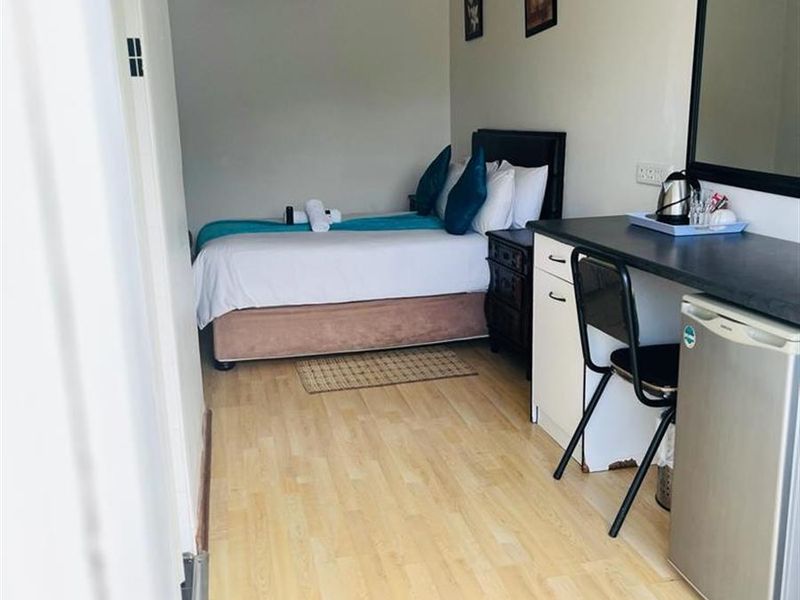 A compact bedroom featuring laminate flooring, an integrated desk area, and a wall-mounted air conditioning unit.