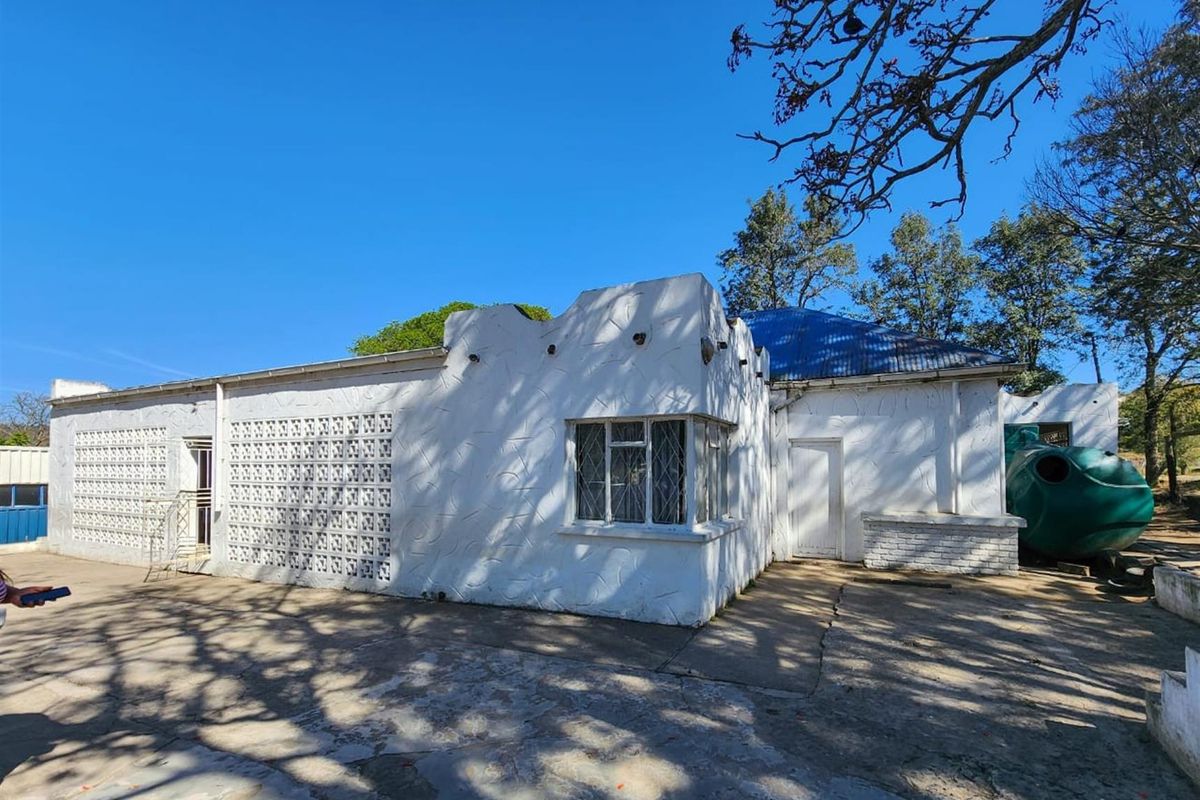 Rear exterior view of the property featuring a white masonry facade with decorative breeze blocks, security window bars, and an adjacent water storage tank.