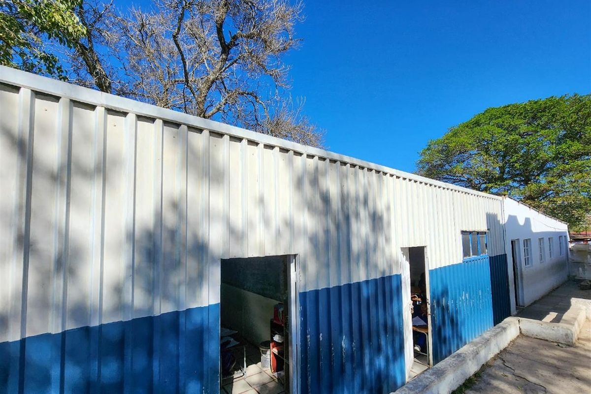 Exterior view of a commercial building featuring corrugated metal cladding with blue and white paint, showing signs of wear and weathering.