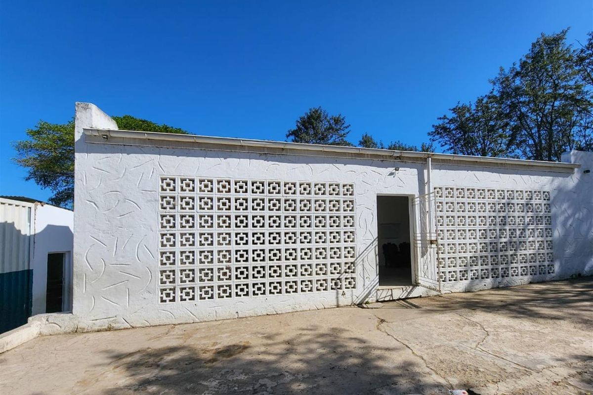 Rear exterior view of the building featuring decorative breeze block walling and concrete paved area.