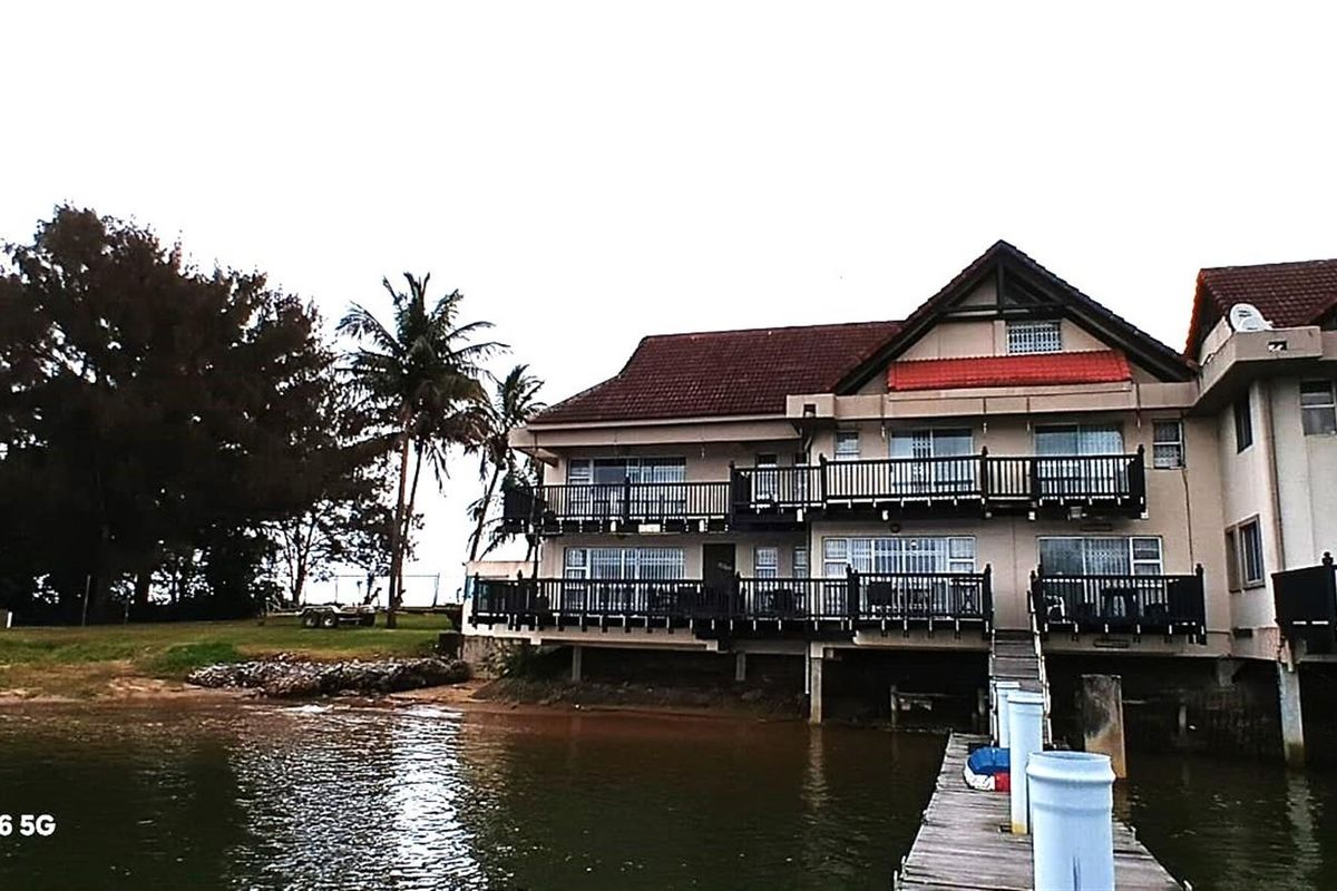 Waterfront property featuring multi-level balconies, tiled roof, and direct access to a private jetty on the water.