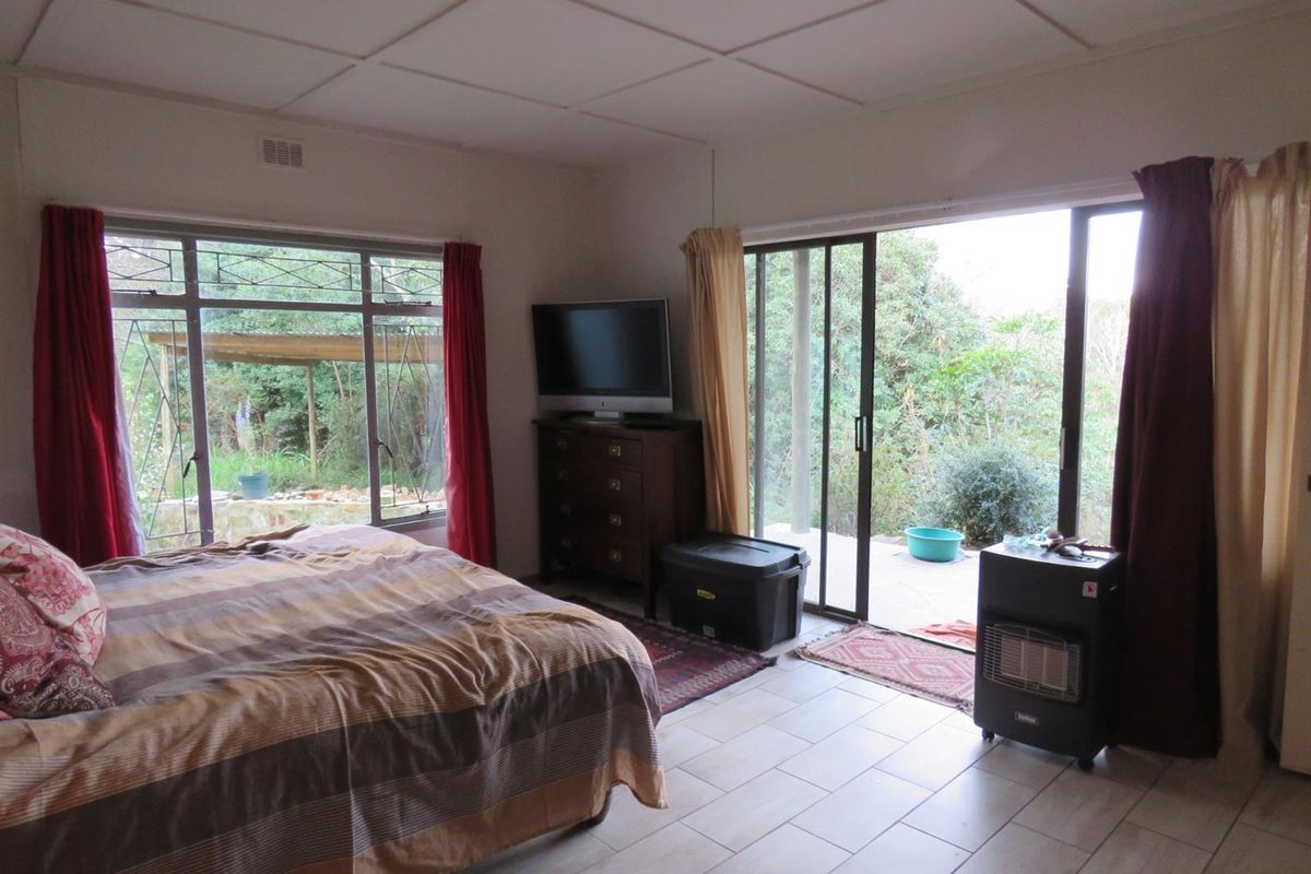 Spacious bedroom featuring large windows and sliding glass doors providing direct access to the garden area.