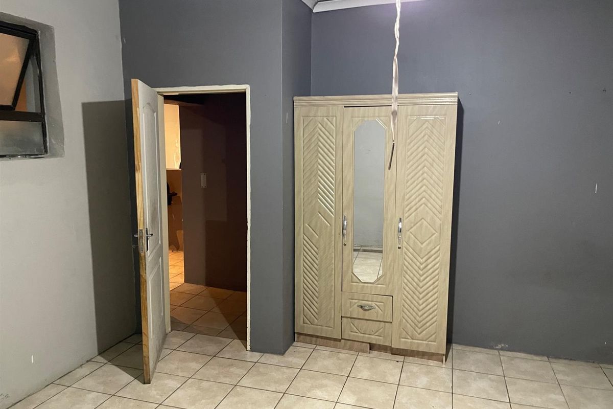 A bedroom featuring tiled flooring, dark grey walls, and a doorway leading to an adjacent space.