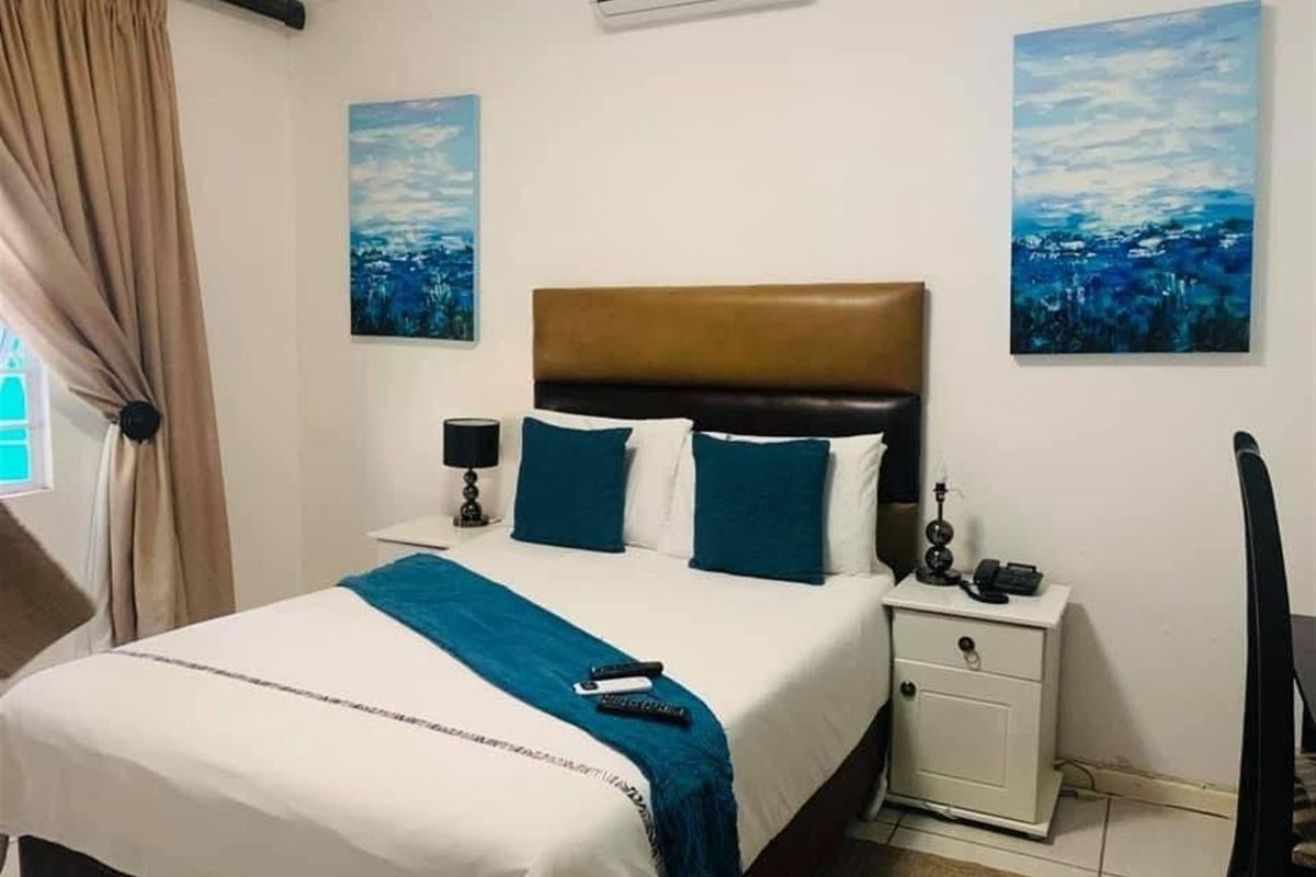 A functional bedroom featuring tiled flooring and a wall-mounted split-system air conditioning unit.