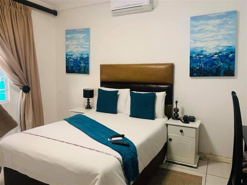 A functional bedroom featuring tiled flooring and a wall-mounted split-system air conditioning unit.