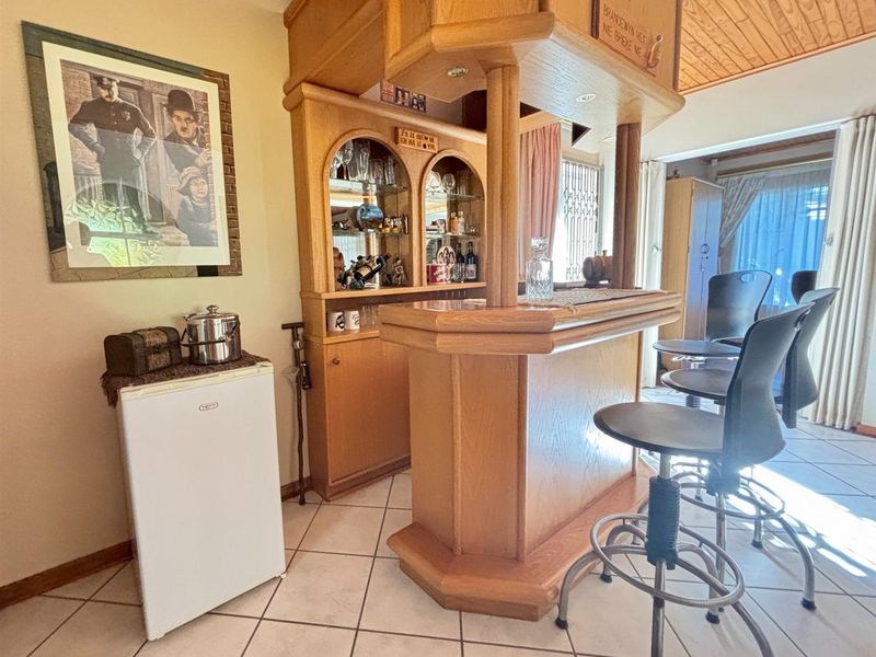 A dedicated home bar area featuring custom built-in wooden cabinetry, a bar counter, tiled flooring, and a timber-clad ceiling.