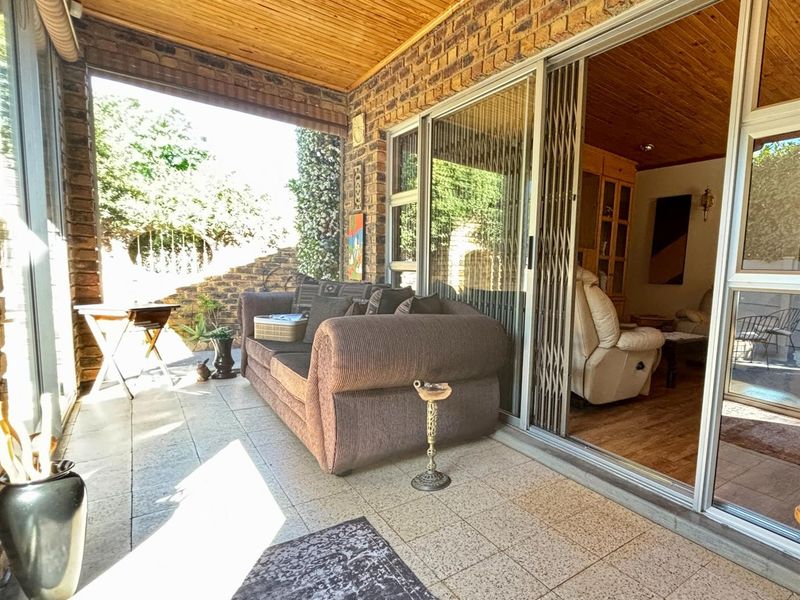 Covered patio area featuring exposed brick walls, timber ceiling, and large sliding glass doors providing access to the interior living space.