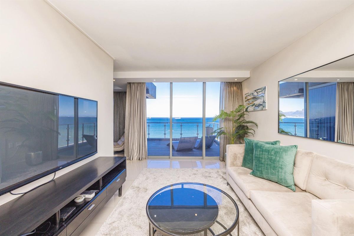 Modern living room featuring large sliding glass doors that open onto a balcony with expansive ocean views.