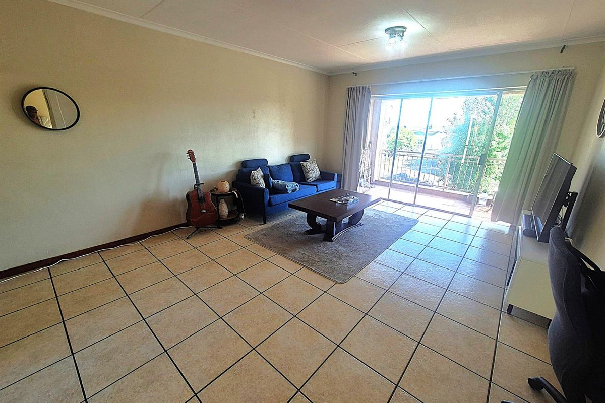 Spacious living area featuring neutral ceramic floor tiles and large sliding glass doors providing access to a private balcony.