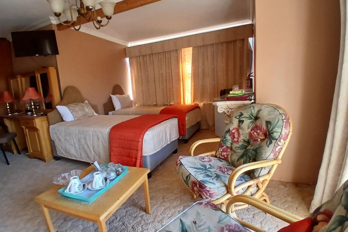 A spacious bedroom featuring neutral wall tones, carpeted flooring, and a classic chandelier, offering a comfortable and functional living space.