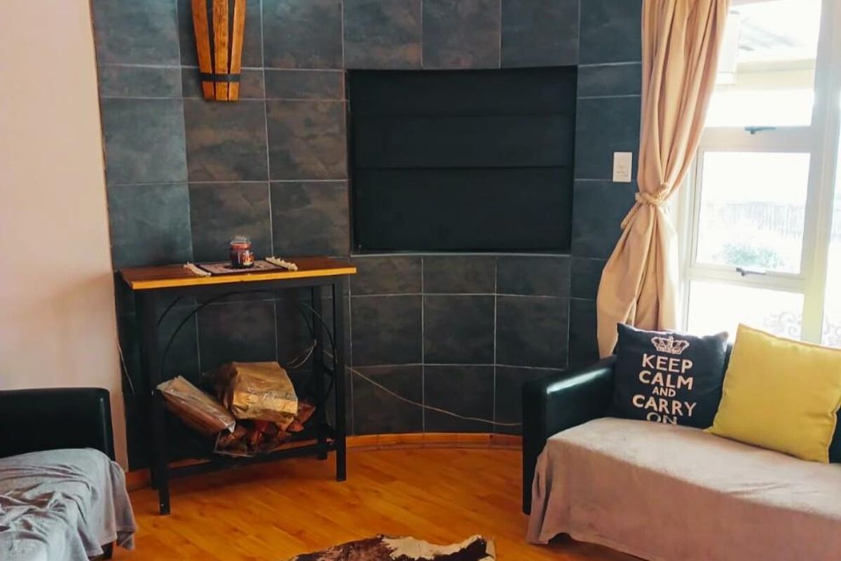A living room featuring a curved feature wall with dark slate-style tiling and a built-in fireplace recess, complemented by light wood flooring.