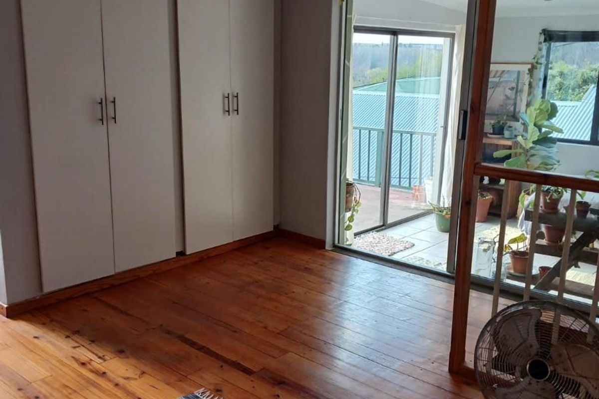 Bedroom featuring polished timber flooring, built-in cupboards, and sliding glass doors providing access to an outdoor balcony area.