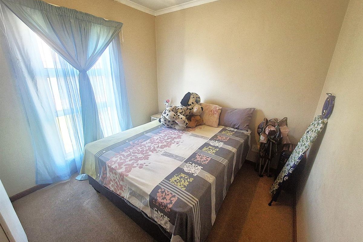 A standard bedroom featuring carpeted flooring, a large window with curtains, and neutral wall finishes.
