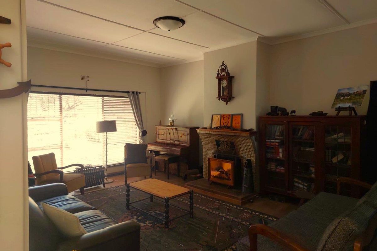 A living room featuring a tiled fireplace hearth, large window with blinds, and a traditional ceiling finish.